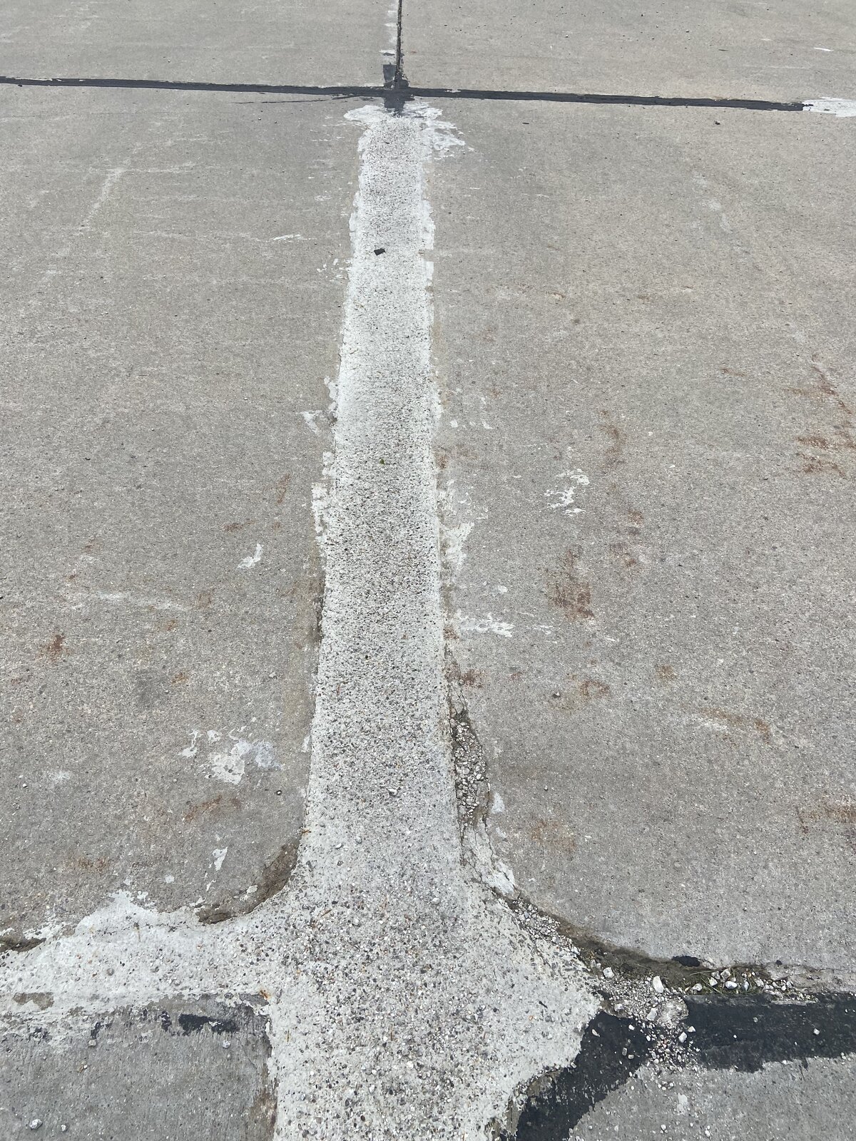 FibreCrete polymer joint repair on concrete — gray polymer mix with small aggregate visibly patched across concrete panel joint by Asphalt Fabrics & Specialties