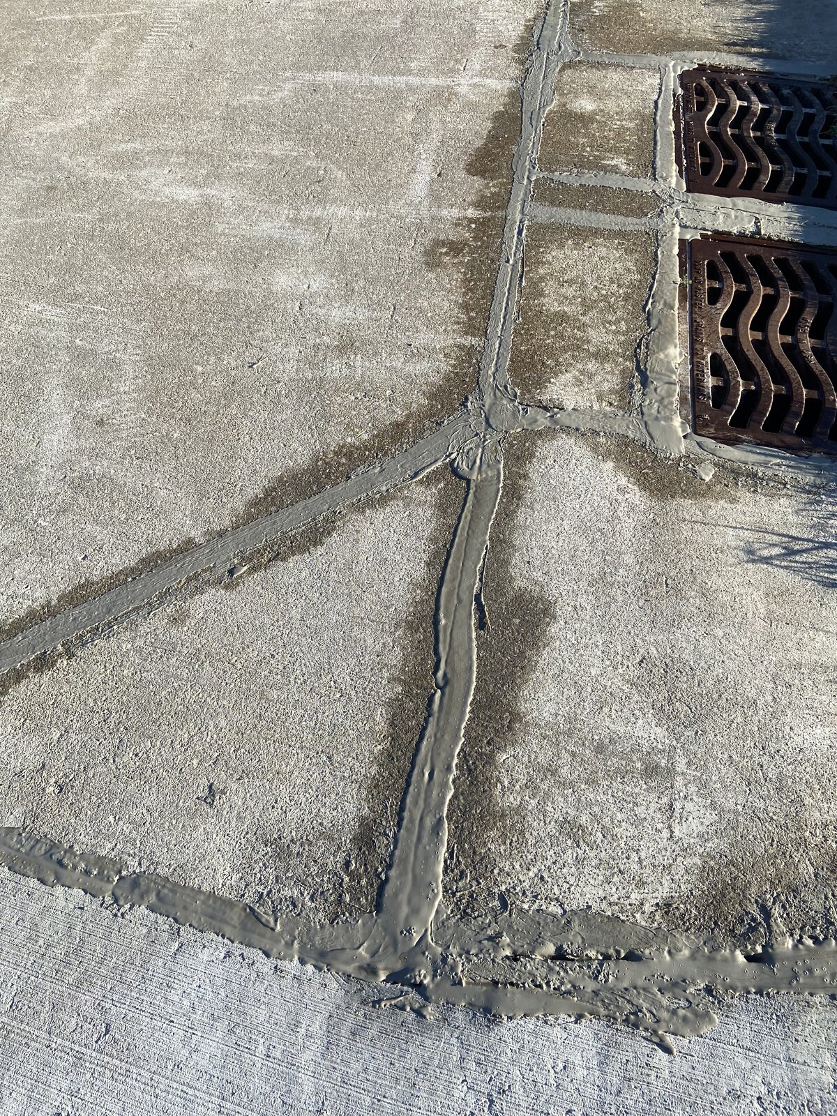 Gray Crack Seal on concrete surface — rubberized Type 2 sealant applied by Asphalt Fabrics & Specialties, color-matched to concrete, no black asphalt lines